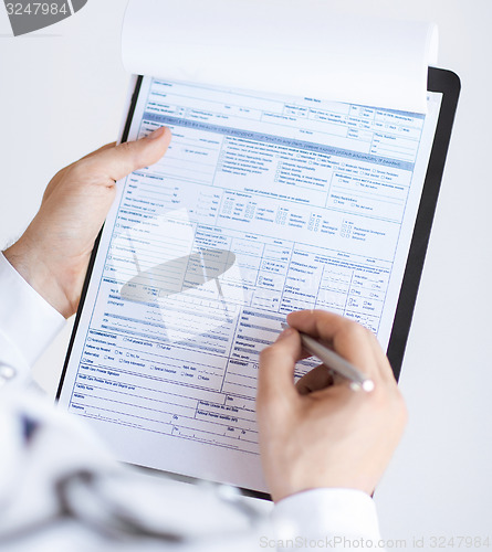 Image of male doctor holding prescription paper in hand