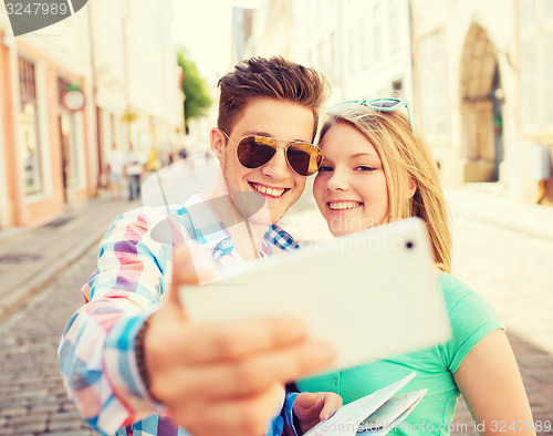 Image of smiling couple with smartphone in city