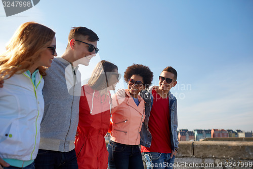Image of happy teenage friends walking along city street