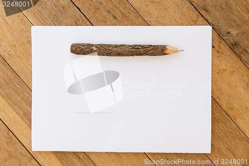 Image of white blank paper sheet with wooden pen on table 