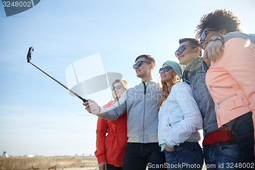 Image of smiling friends taking selfie with smartphone