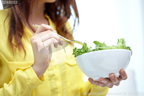 Image of close up of young woman eating salad at home