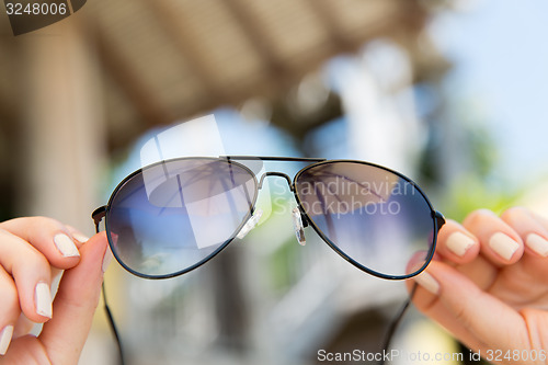 Image of close up of hands holding shades or sunglasses