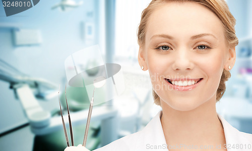 Image of happy young female dentist with tools