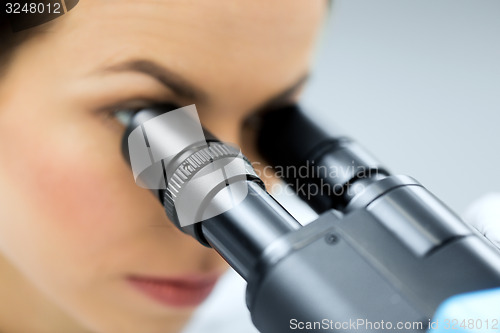 Image of close up of scientist looking to microscope in lab