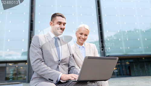 Image of smiling businesspeople with laptop outdoors