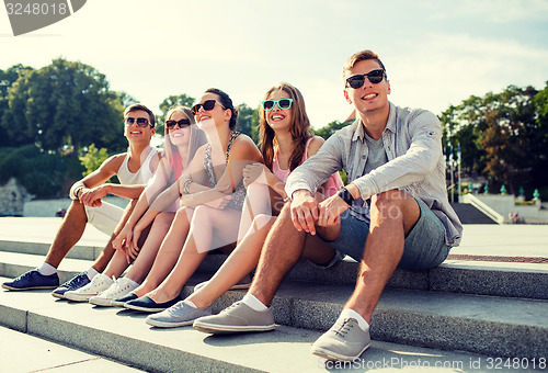 Image of group of smiling friends sitting on city street
