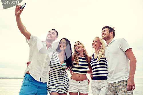 Image of happy friends on beach and taking selfie
