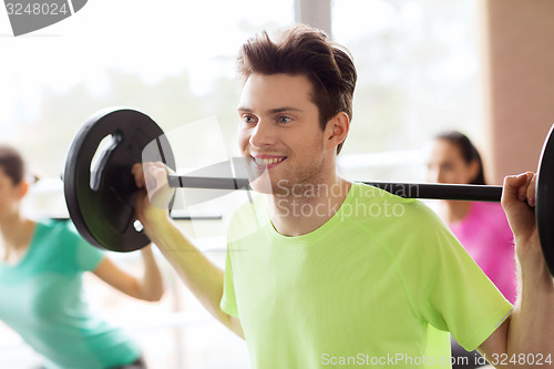 Image of group of people exercising with barbell in gym