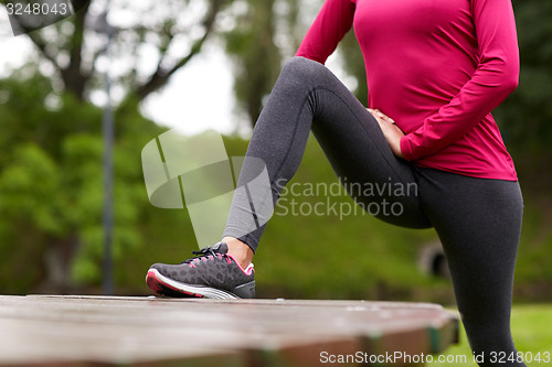 Image of close up of woman stretching leg outdoors