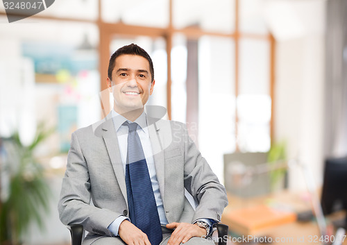 Image of happy businessman sitting in office chair