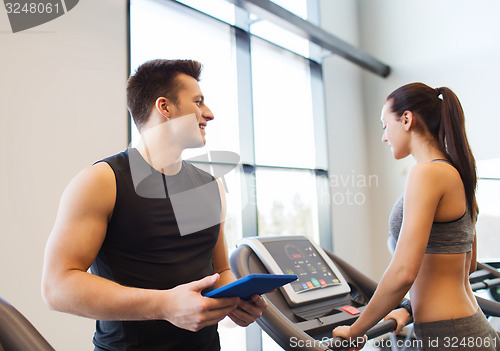 Image of happy woman with trainer on treadmill in gym