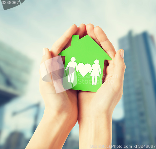 Image of hands holding green house with family