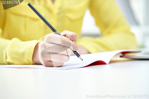 Image of close up of female hands writing to notebook