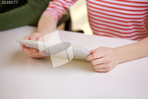 Image of close up of female hands with tablet pc at table