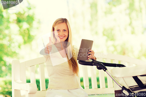 Image of happy mother with tablet pc and stroller in park