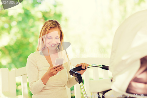 Image of happy mother with smartphone and stroller in park