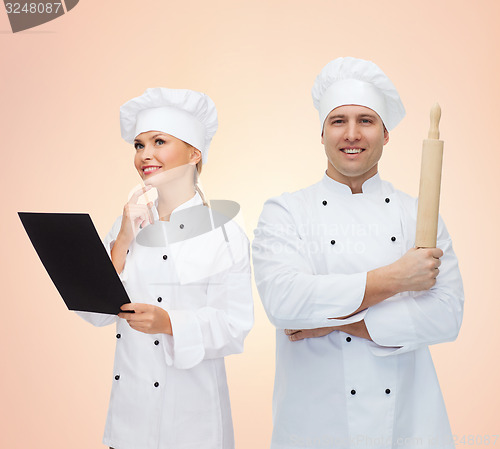 Image of happy chefs or cooks couple holding rolling pin