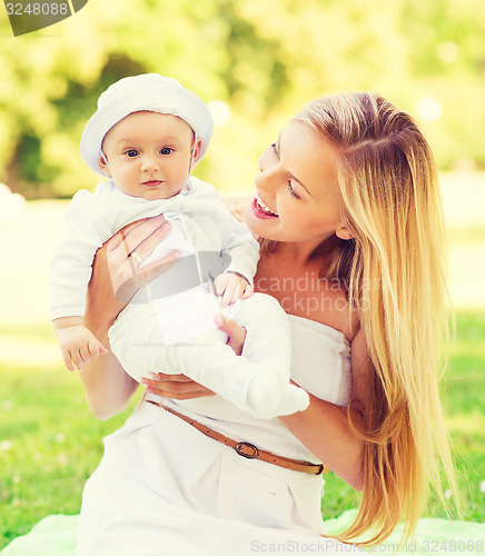 Image of happy mother with little baby sitting on blanket