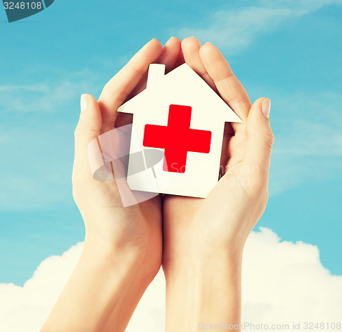 Image of hands holding paper house with red cross