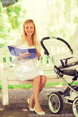 Image of happy mother with book and stroller in park