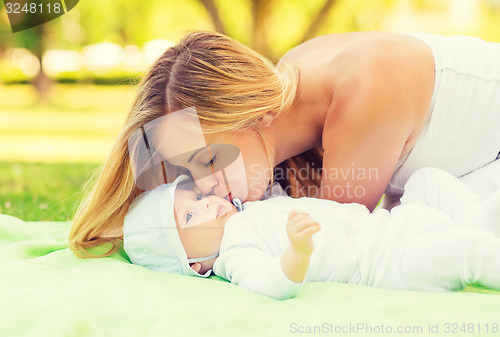 Image of happy mother lying with little baby on blanket