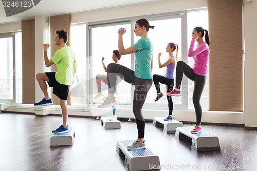 Image of group of people working out with steppers in gym