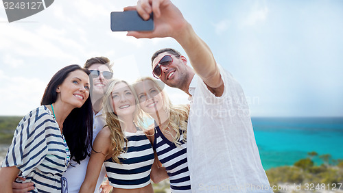 Image of friends on beach taking selfie with smartphone