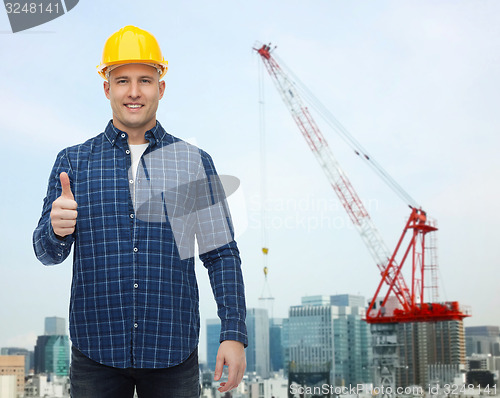 Image of smiling male builder in helmet showing thumbs up