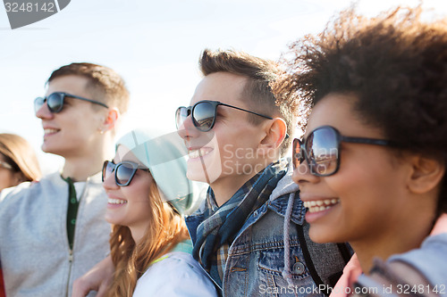 Image of happy teenage friends in shades hugging outdoors