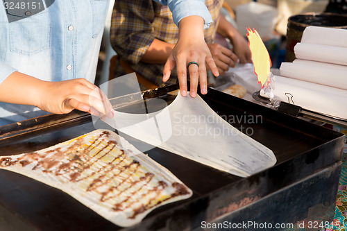 Image of close up of cook frying pancakes at street market