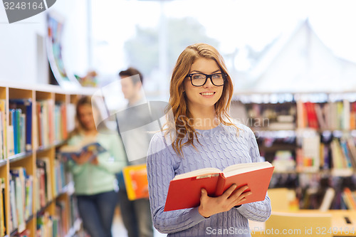 Image of happy student girl or woman with book in library