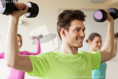 Image of group of smiling people working out with dumbbells