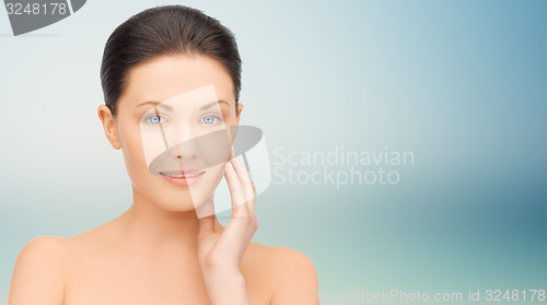 Image of beautiful young woman touching her face