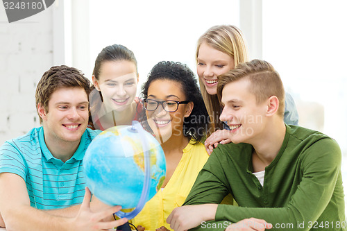 Image of five smiling student looking at globe at school