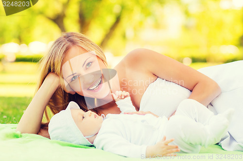 Image of laughing mother lying with little baby on blanket