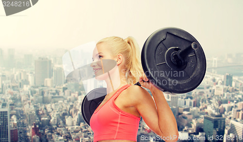 Image of smiling sporty woman exercising with barbell