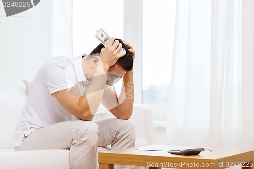 Image of man with money and calculator at home