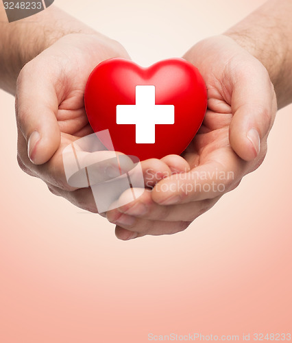 Image of male hands holding red heart with white cross