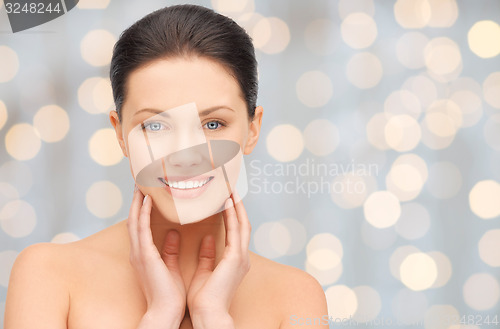 Image of beautiful young woman touching her face and neck