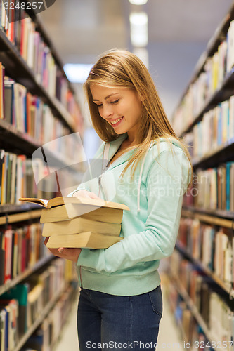 Image of happy student girl or woman with book in library