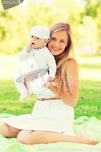 Image of happy mother with little baby sitting on blanket