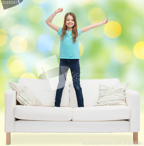 Image of smiling little girl jumping on sofa