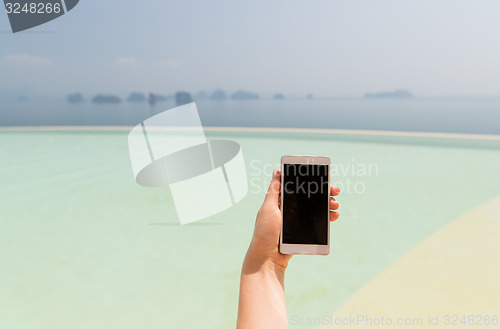Image of close up of female hand with smartphone on beach