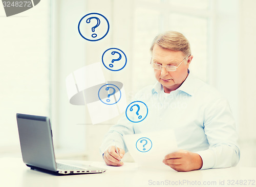 Image of old man in eyeglasses filling a form at home