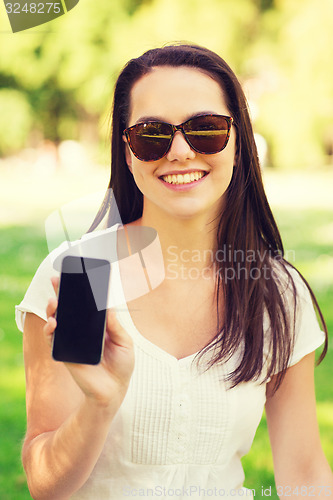 Image of smiling young girl with smartphone outdoors