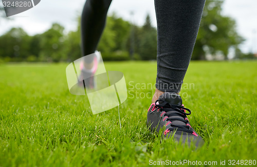 Image of close up of exercising woman legs on grass in park