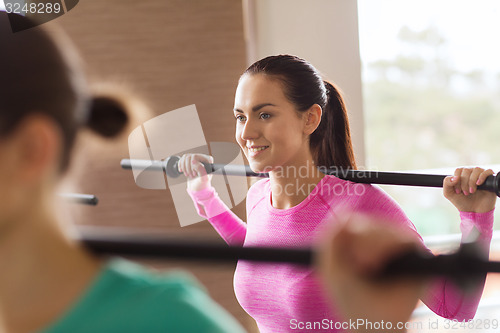 Image of group of people exercising with bars in gym
