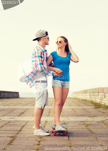 Image of smiling couple with skateboard outdoors