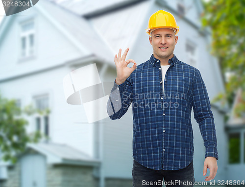 Image of smiling male builder in helmet showing ok sign